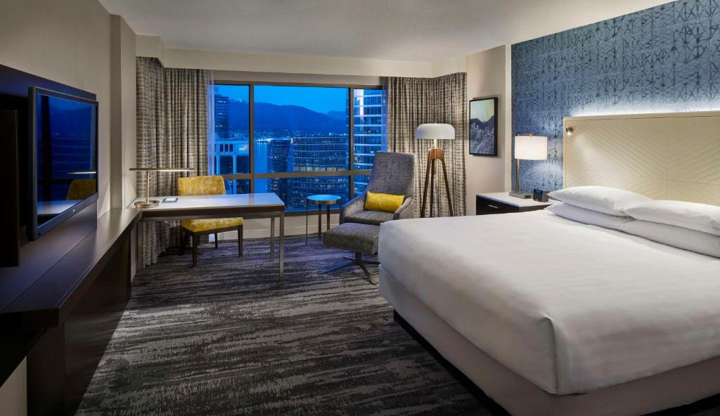 a hotel room with a bed and a desk with a view at Hyatt Regency Vancouver in Vancouver