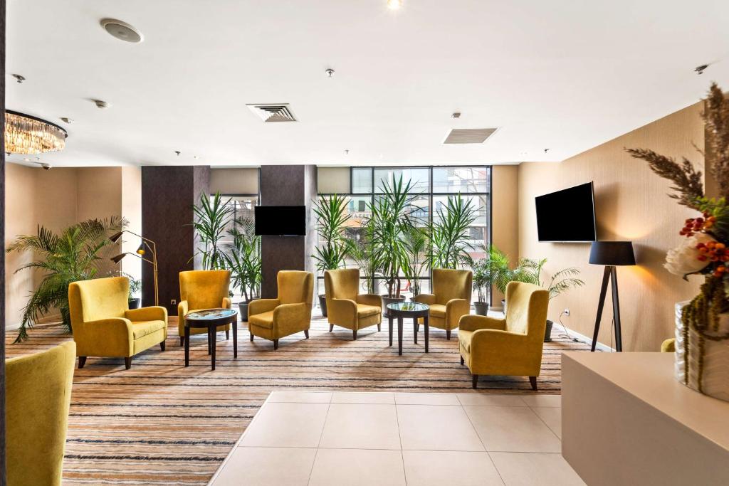 a waiting room with yellow chairs and tables at Hampton by Hilton Cluj-Napoca in Cluj-Napoca