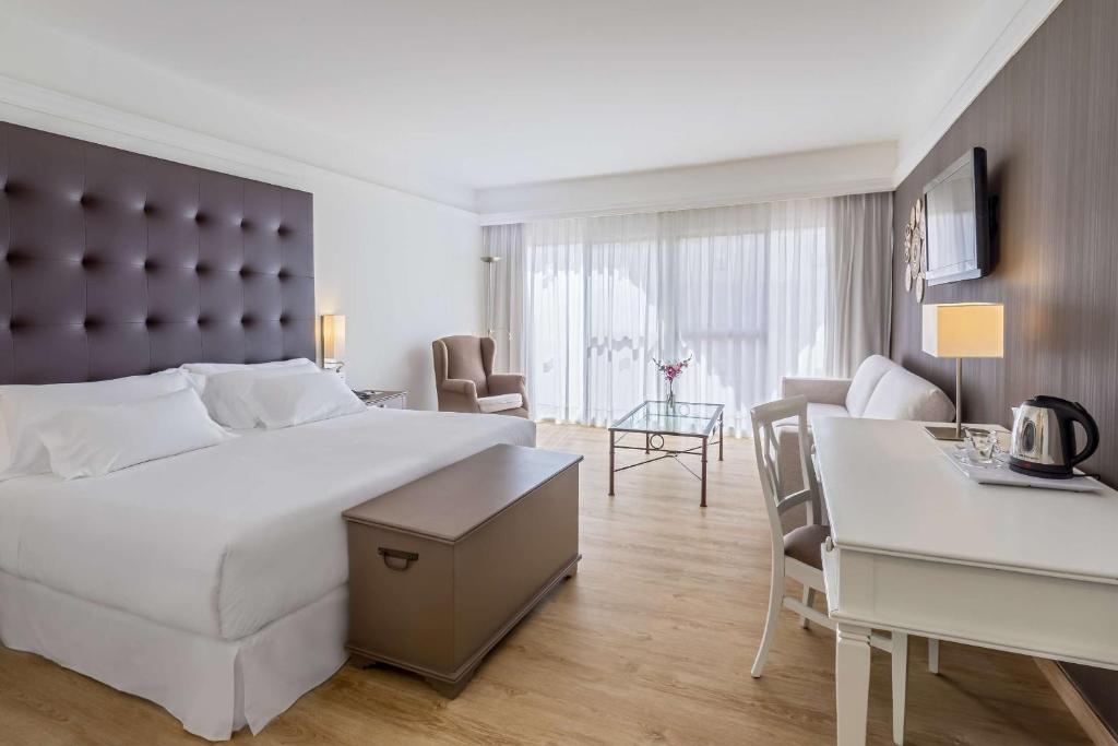 a hotel room with a large bed and a desk at Barceló Corralejo Bay - Adults Only in Corralejo