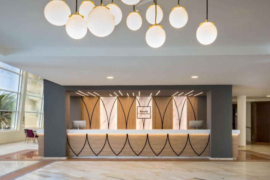 a lobby with a waiting area and chandeliers at Barceló Corralejo Bay - Adults Only in Corralejo