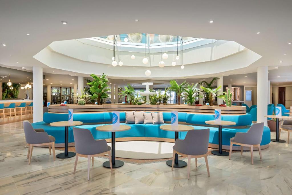 a lobby of a hotel with blue tables and chairs at Barceló Corralejo Bay - Adults Only in Corralejo