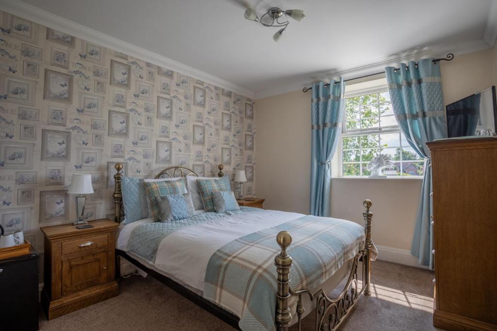 a bedroom with a bed with blue curtains and a window at Harmony House Boutique B&B in Stillingfleet