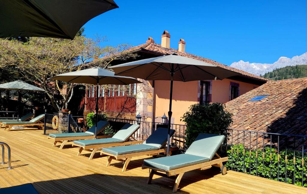 a group of lounge chairs and umbrellas on a deck at Apartamentos Villa de Potes in Potes