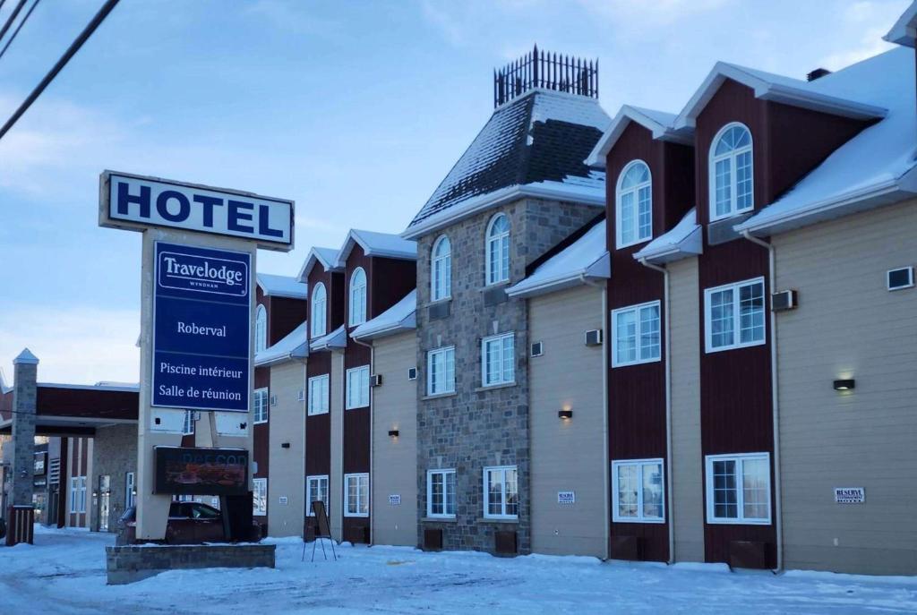un panneau d'hôtel devant un bâtiment dans la neige dans l'établissement Travelodge by Wyndham Roberval, à Roberval