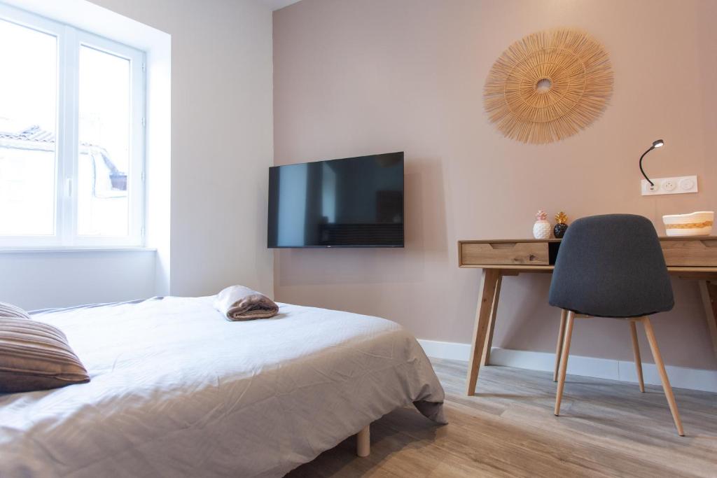 um quarto com uma cama, uma secretária e uma televisão em Le Refuge Valencien - Douceur et Élégance em Valence-sur-Baïse