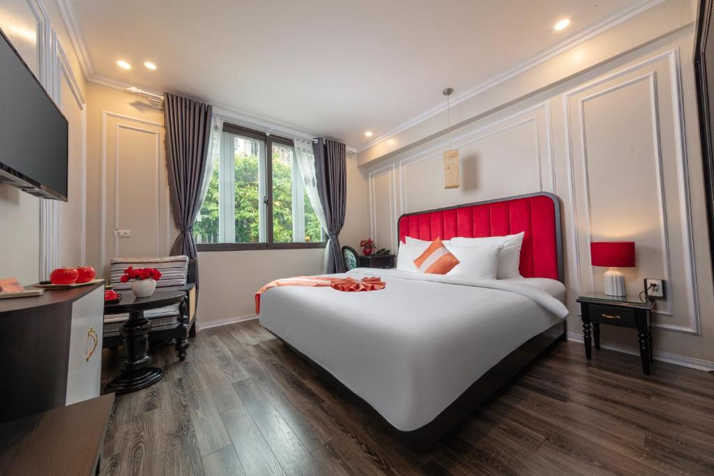 Omina Hanoi Hotel & Travel في هانوي: غرفة نوم مع سرير أبيض كبير مع اللوح الأمامي الأحمر