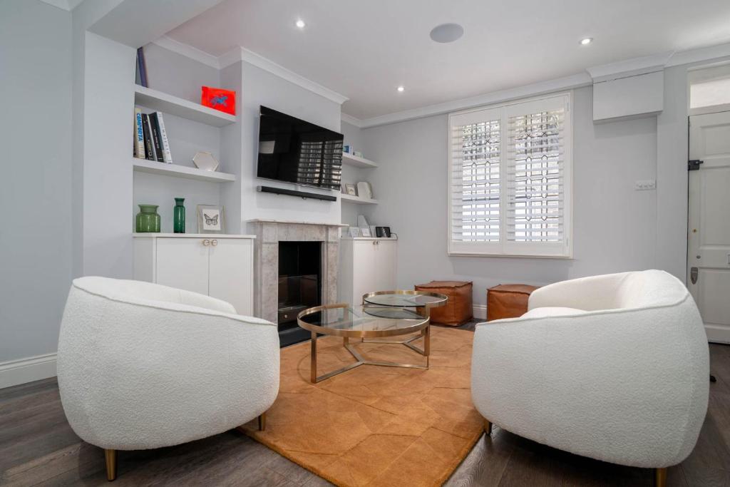 sala de estar con 2 sillas blancas y mesa en GuestReady - Modern Apt in Chelsea with a Terrace, en Londres