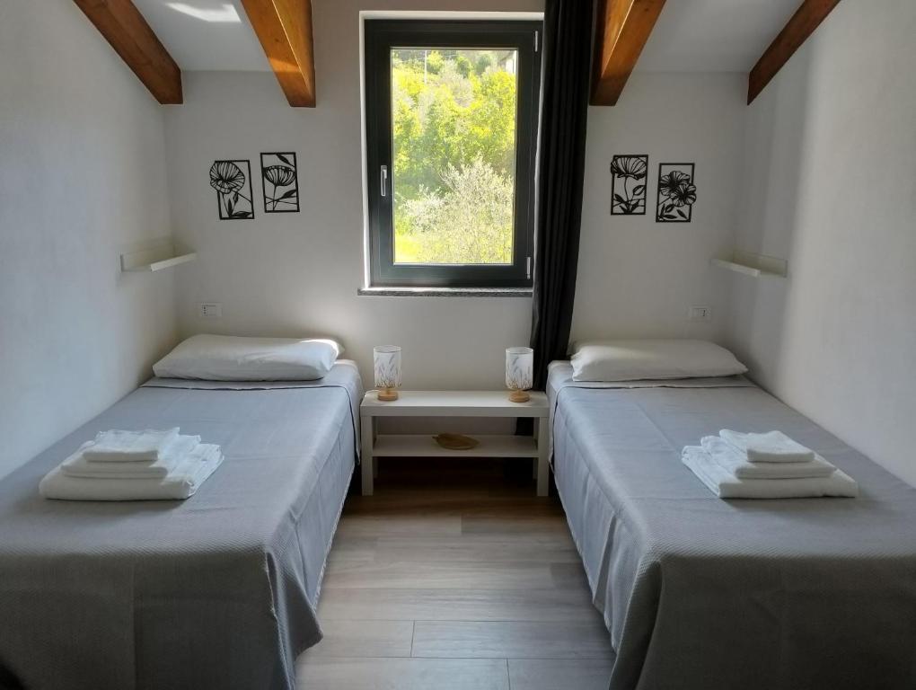 2 camas individuais num quarto com uma janela em Casa Marta 11 em Garlenda