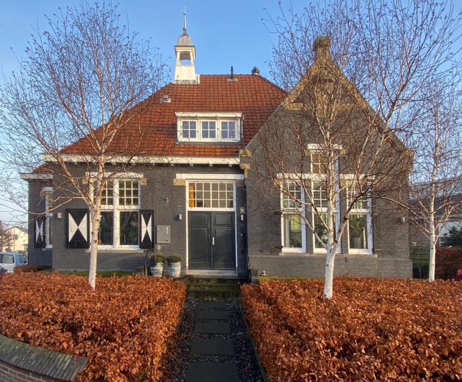 una casa con una torre dell'orologio sopra di Het Oude Raadhuis a Noordwijkerhout