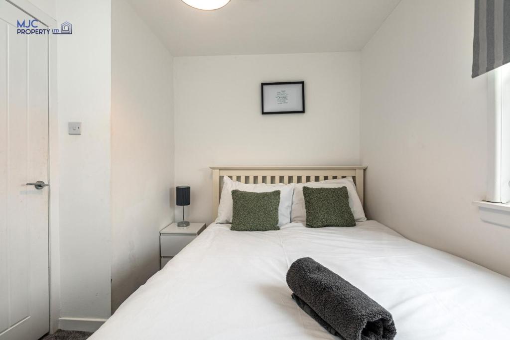 a bedroom with a white bed with a pillow on it at Town Centre Apartment in Hawick