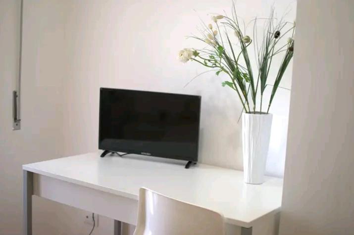 - un bureau blanc avec un vase de fleurs dans l'établissement Maison Salerno, à Salerne