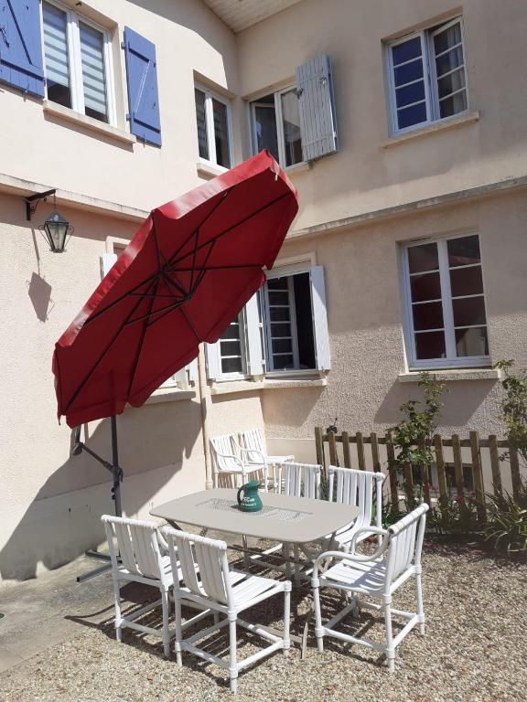 une table et des chaises avec un parasol rouge dans l'établissement Maison Quebec, à Bernières-sur-Mer