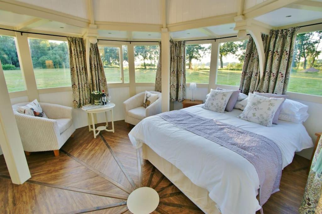 1 dormitorio con 1 cama, sillas y ventanas en The Folly - one off luxury Glamping accommodation, en Norwich