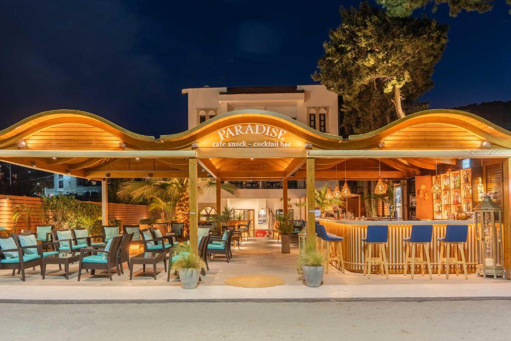 un restaurante con sillas y un bar por la noche en Paradise Hotel-Apartments, en Stalida