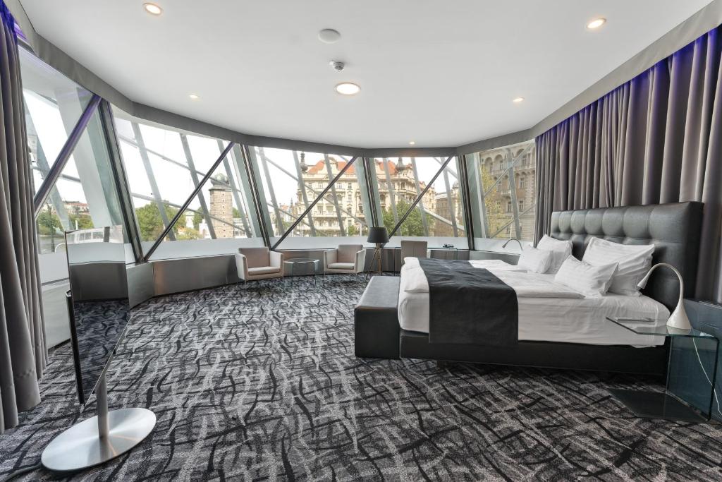 a bedroom with a large bed and large windows at Dancing House - Tančící dům hotel in Prague