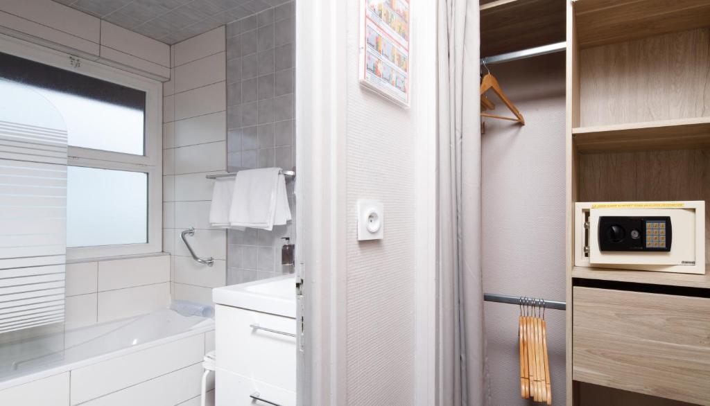 a white bathroom with a sink and a microwave at Saint Aubin Logis Hôtel & Restaurant in Saint-Aubin-sur-Mer