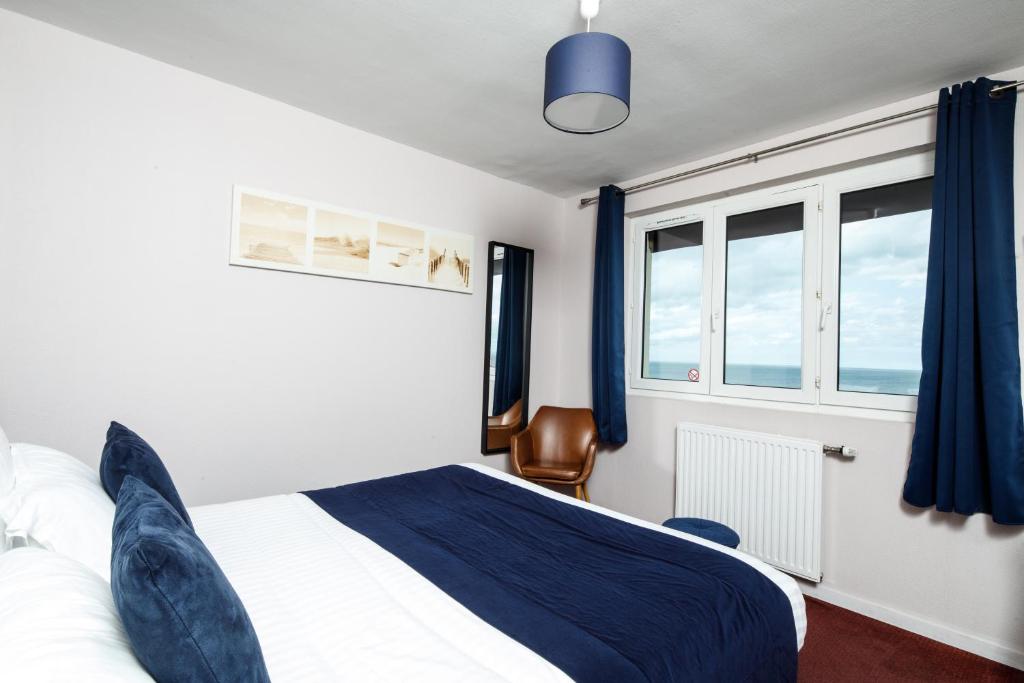 a bedroom with a blue and white bed and a window at Saint Aubin Logis Hôtel & Restaurant in Saint-Aubin-sur-Mer