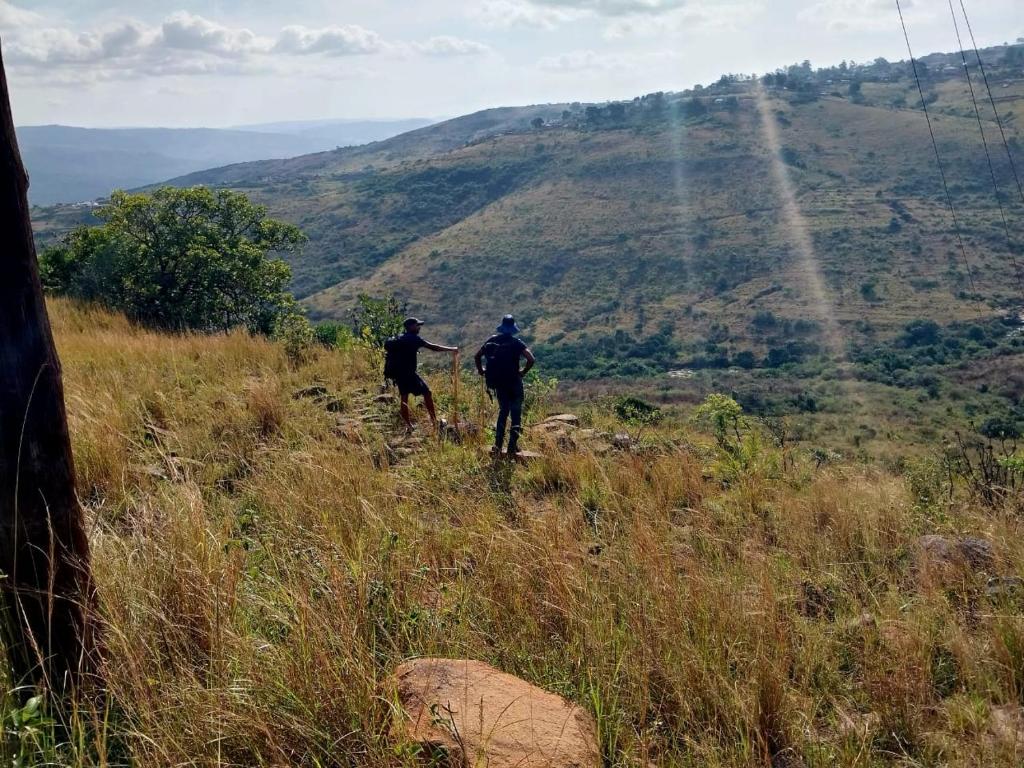 two people walking up a hill on a mountain at Qabuleka BnB in Nongoma