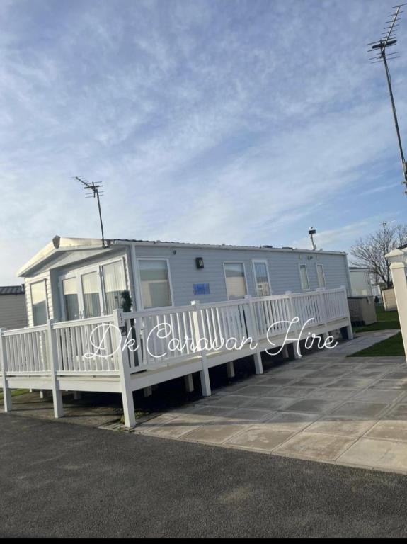 una casa móvil con una valla blanca y una casa en Luxury Caravan in Towyn North Wales, en Abergele