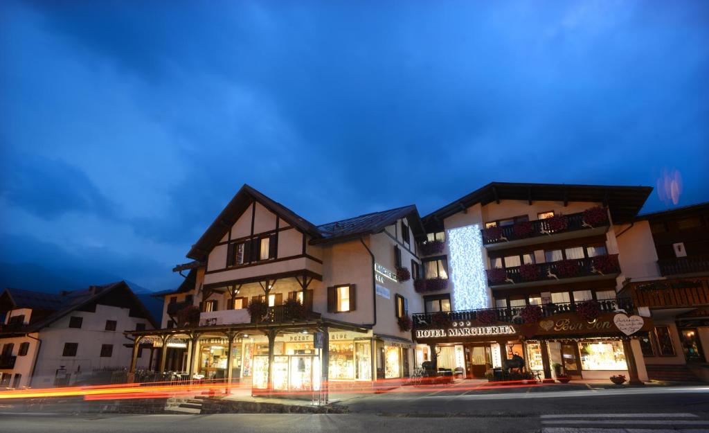 a building with lights on the side of a street at Hotel Margherita in San Martino di Castrozza