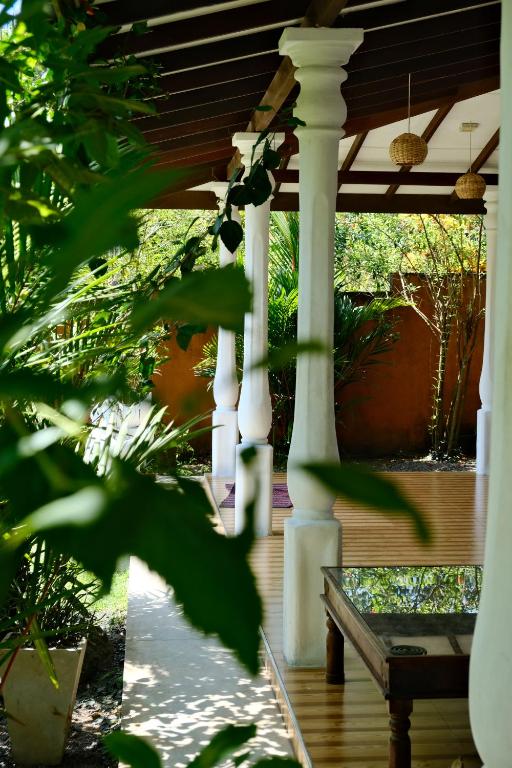 een houten veranda met een pergola en een bank bij One Bhakthi in Ahangama