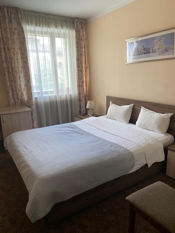 a bedroom with a large white bed with a window at Санаторий Казахстан in Gornyy Gigant