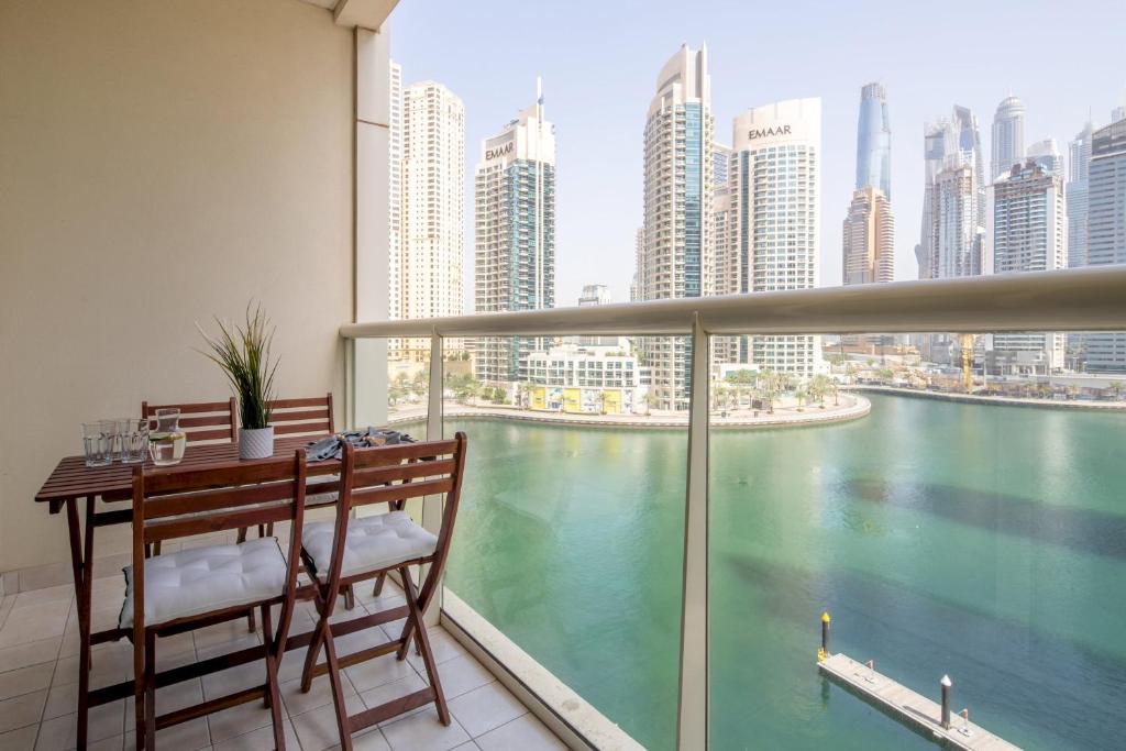een balkon met een tafel en stoelen en uitzicht op het water bij Frank Porter - Marina Views Tower in Dubai