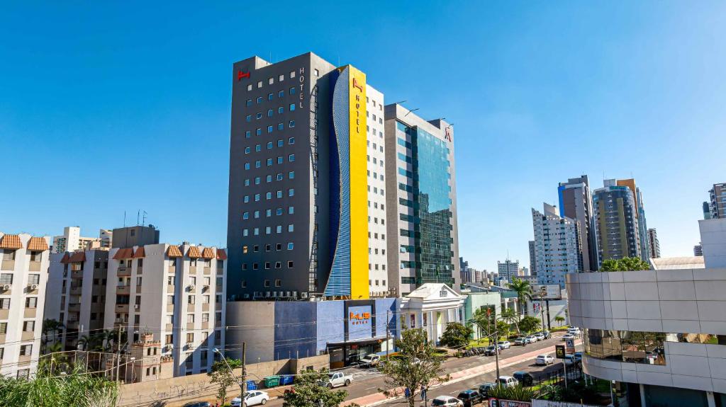 ein hohes Gebäude in einer Stadt mit Gebäuden in der Unterkunft HUS Hotel MARINGA in Maringá