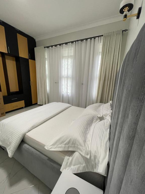 1 dormitorio con 1 cama con sábanas blancas y ventana en Mayvad Homes, en Kampala