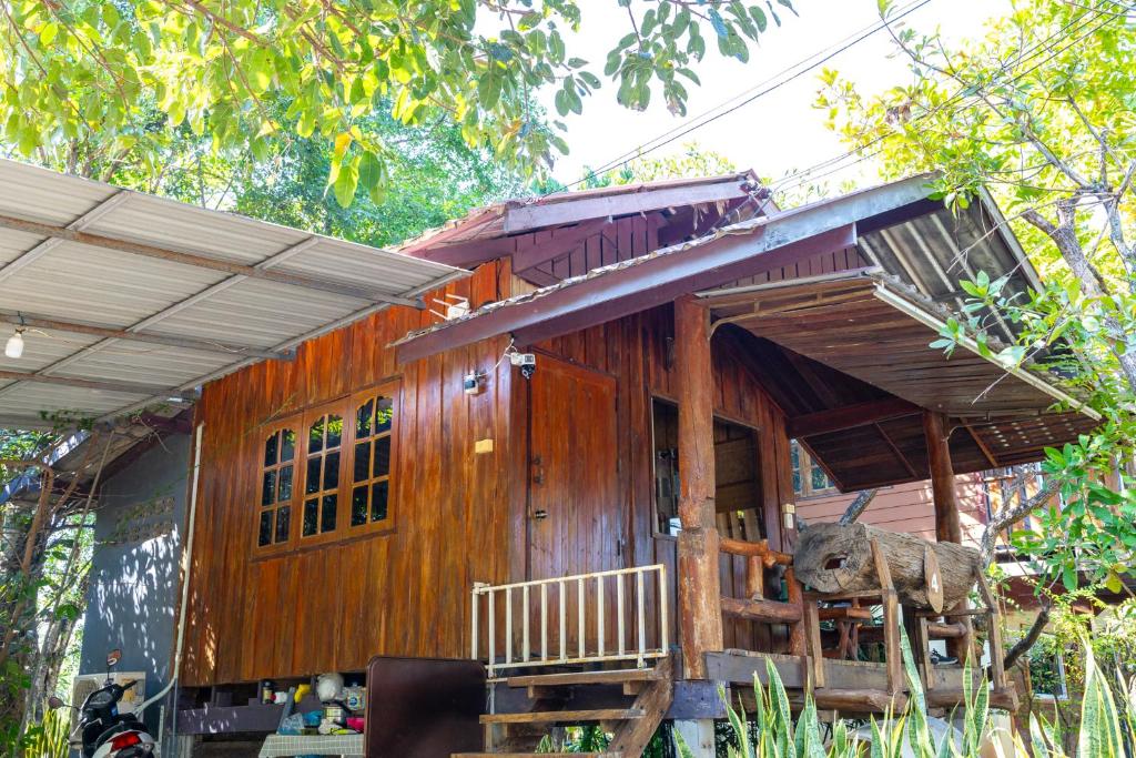 ein kleines Holzhaus mit einer Statue davor in der Unterkunft Ruenpakkiangnan เรือนพักเคียงน่าน in Phitsanulok