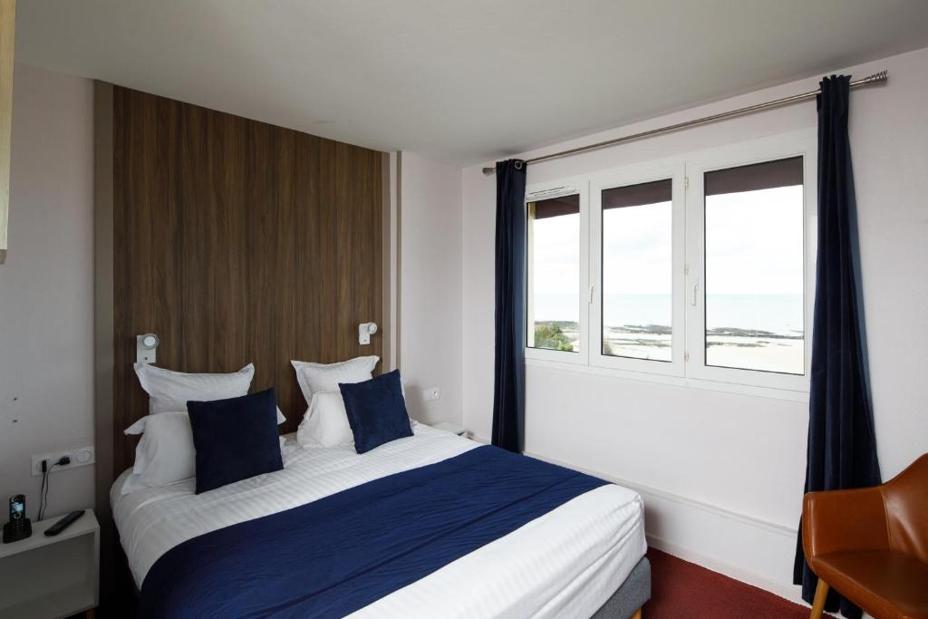 a bedroom with a bed with blue and white pillows at Saint Aubin Logis Hôtel & Restaurant in Saint-Aubin-sur-Mer