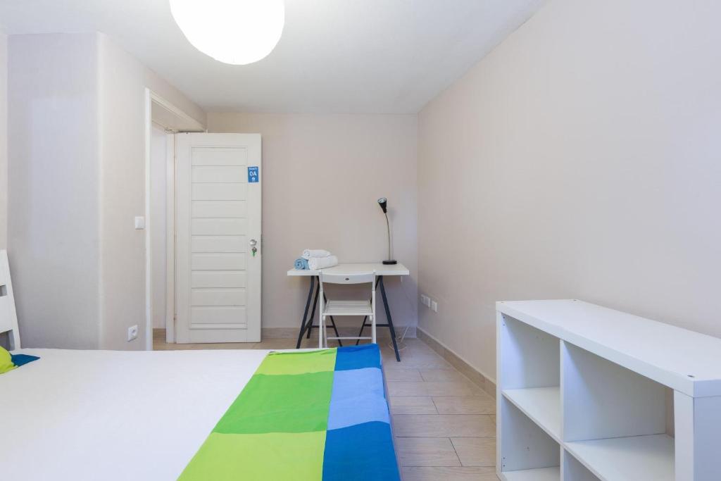 a white room with a bed and a desk at Relógio Guest House in Porto
