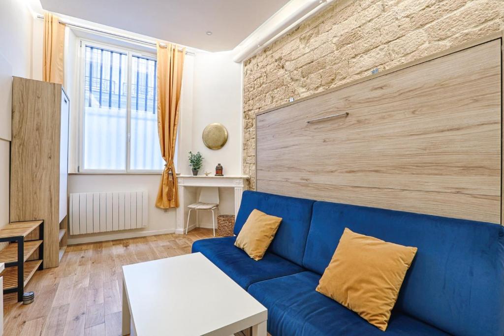 - un salon avec un canapé bleu et un mur en briques dans l'établissement Beau studio 2P en plein cœur du 2e, à Paris