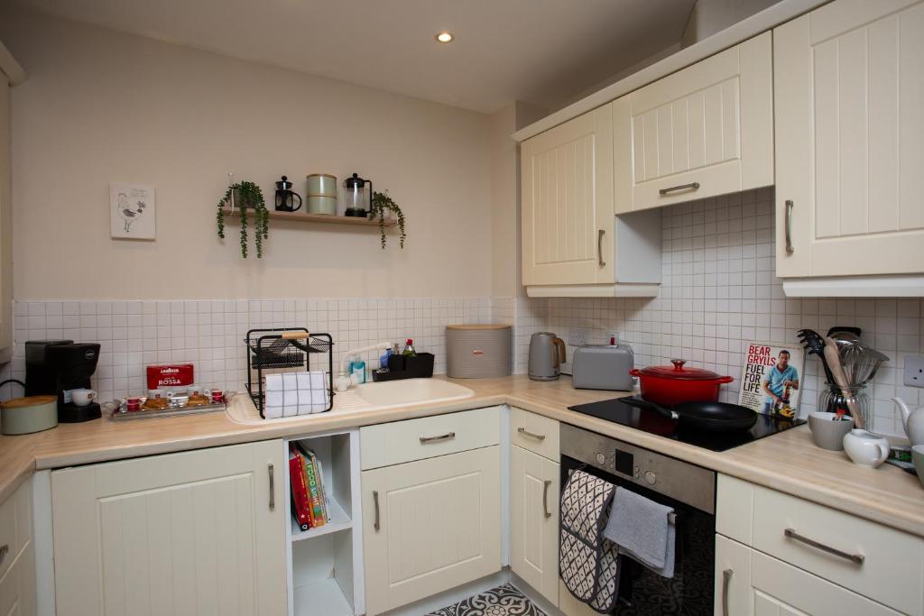 uma cozinha com armários brancos e um forno com placa de fogão em Charming 2-bedroom Apartment Durham em Durham