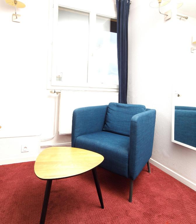 a blue chair and a table in a room at Saint Aubin Logis Hôtel & Restaurant in Saint-Aubin-sur-Mer