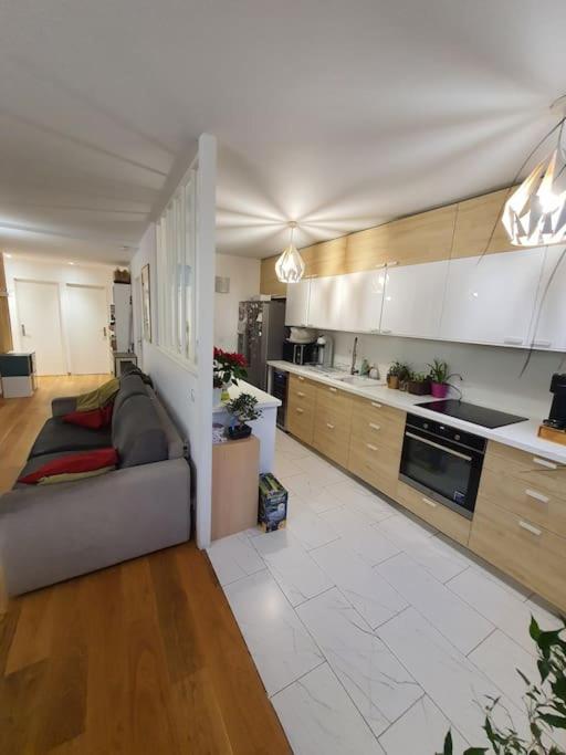 un salon avec un canapé et une cuisine dans l'établissement App 8pers-Proche Paris-Tt équipé, à Montreuil