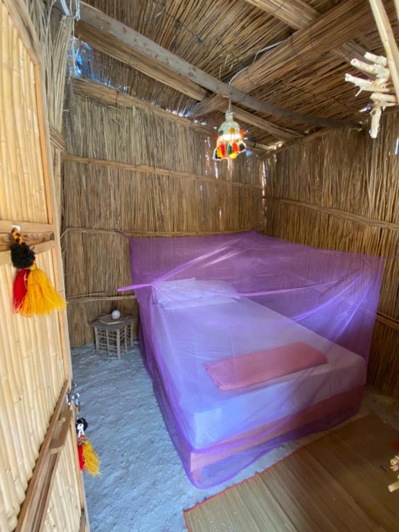 a purple bed in a room with a wooden ceiling at Paloma Camp in Siwa