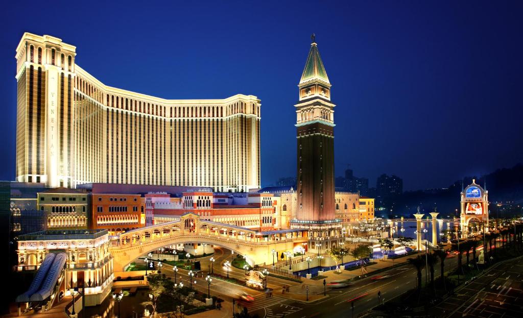 The Venetian Macao Resort Hotel في ماكاو: اطلالة على مدينة بالليل مع برج الساعة