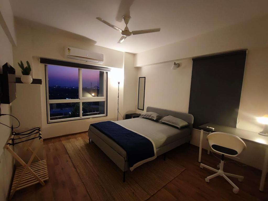 a bedroom with a bed and a desk and a window at Alpha Room in Ahmedabad