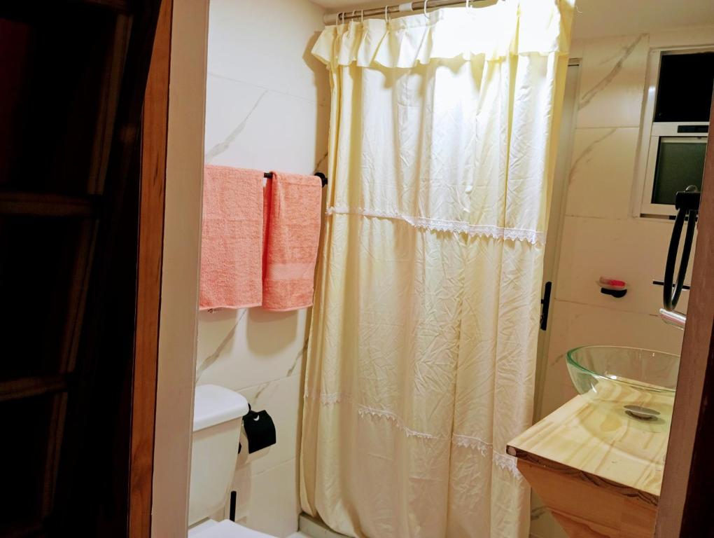 y baño con cortina de ducha y aseo. en Hermosa cabaña con excelente vista panorámica, en Piriápolis