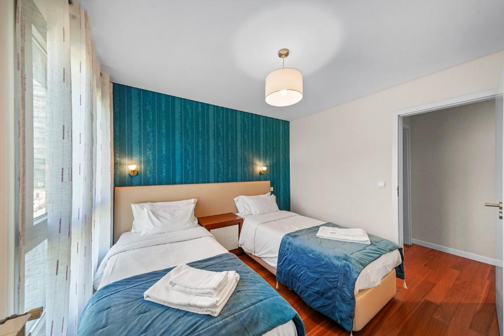 Un dormitorio con dos camas y una pared azul. en Bessa Luxury Flat by Amber Star Rent, en Oporto