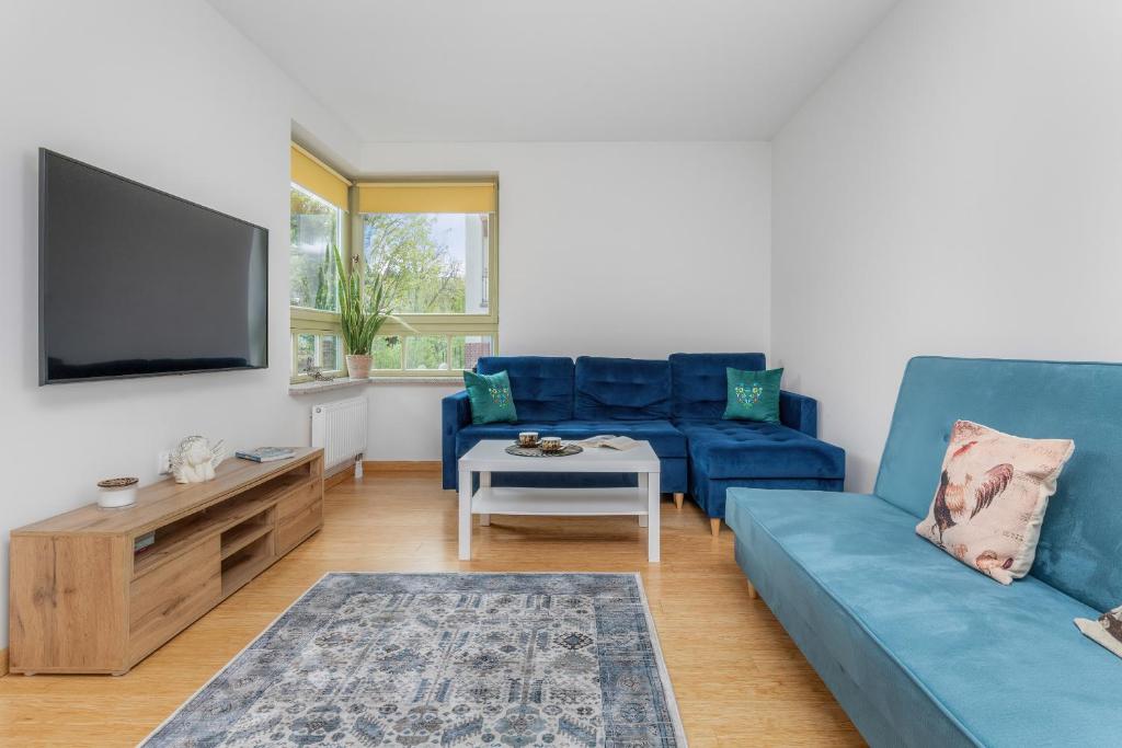 a living room with a blue couch and a tv at Seaside Apartment with Parking in Sopot by Renters in Sopot