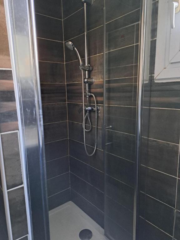 a shower in a bathroom with black tiles at Chambre Solo Duo 20 min Paris - G in Drancy