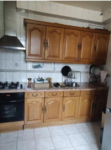 a kitchen with wooden cabinets and a sink at Chambre Solo Duo 20 min Paris - G in Drancy