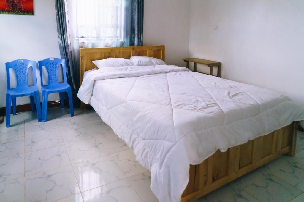 a bedroom with a large bed and two blue chairs at Ambokili Farm Country House in Kimana