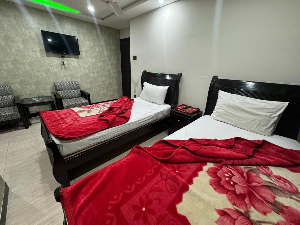 Zimmer mit 2 Betten und roten Decken in der Unterkunft Millat Hotel in Islamabad