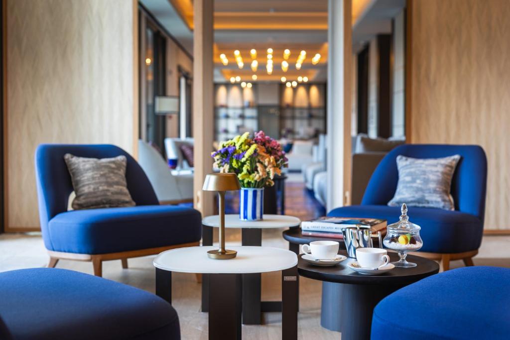 a lobby with blue chairs and tables and flowers at Ara Maris in Sorrento