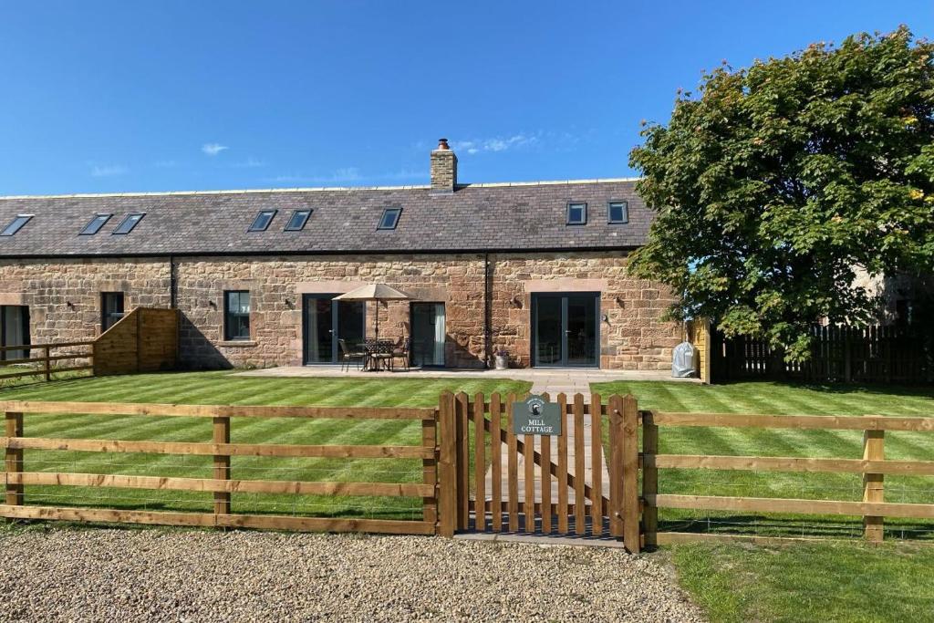 a house with a wooden fence in front of it at Mill Cottage, Brockmill Farm in Berwick-Upon-Tweed