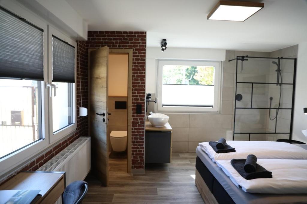 een slaapkamer met een bed en een badkamer met een douche bij Hotel Weilerhof in Dormagen