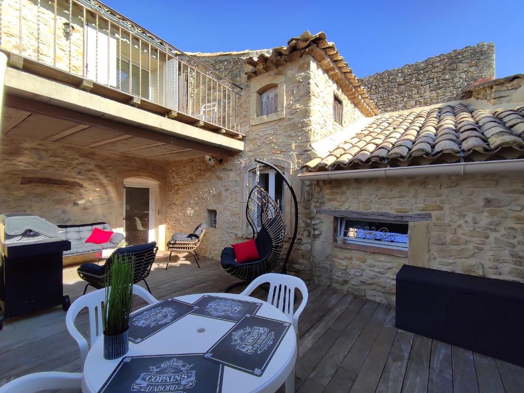 patio ze stołem, krzesłami i kominkiem w obiekcie Maison de village cosy avec terrasse privée w mieście Saint-Marcel-de-Carreiret